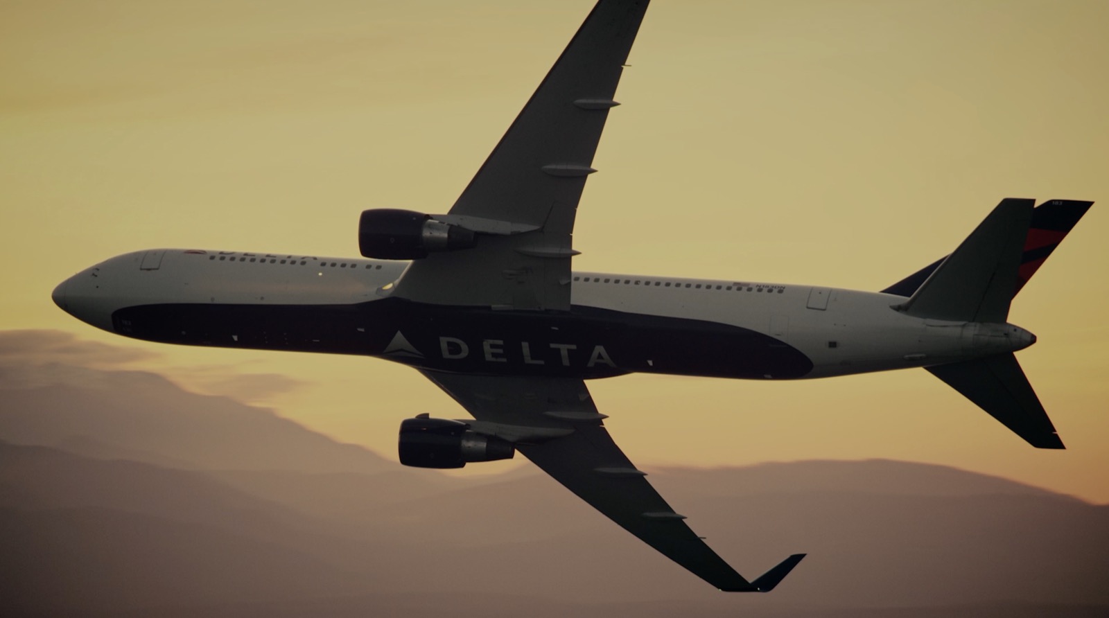 A Delta Air Lines aircraft flying above the mountains