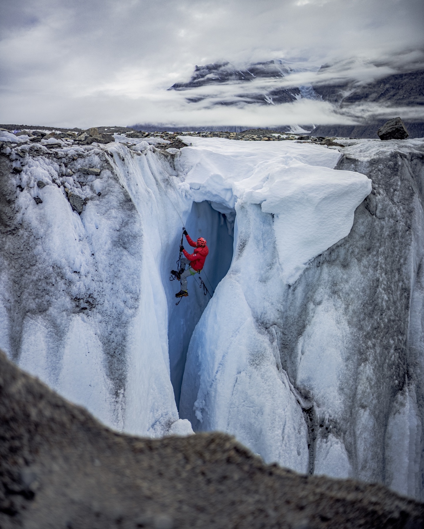 A climber descending into a glacier crevasse