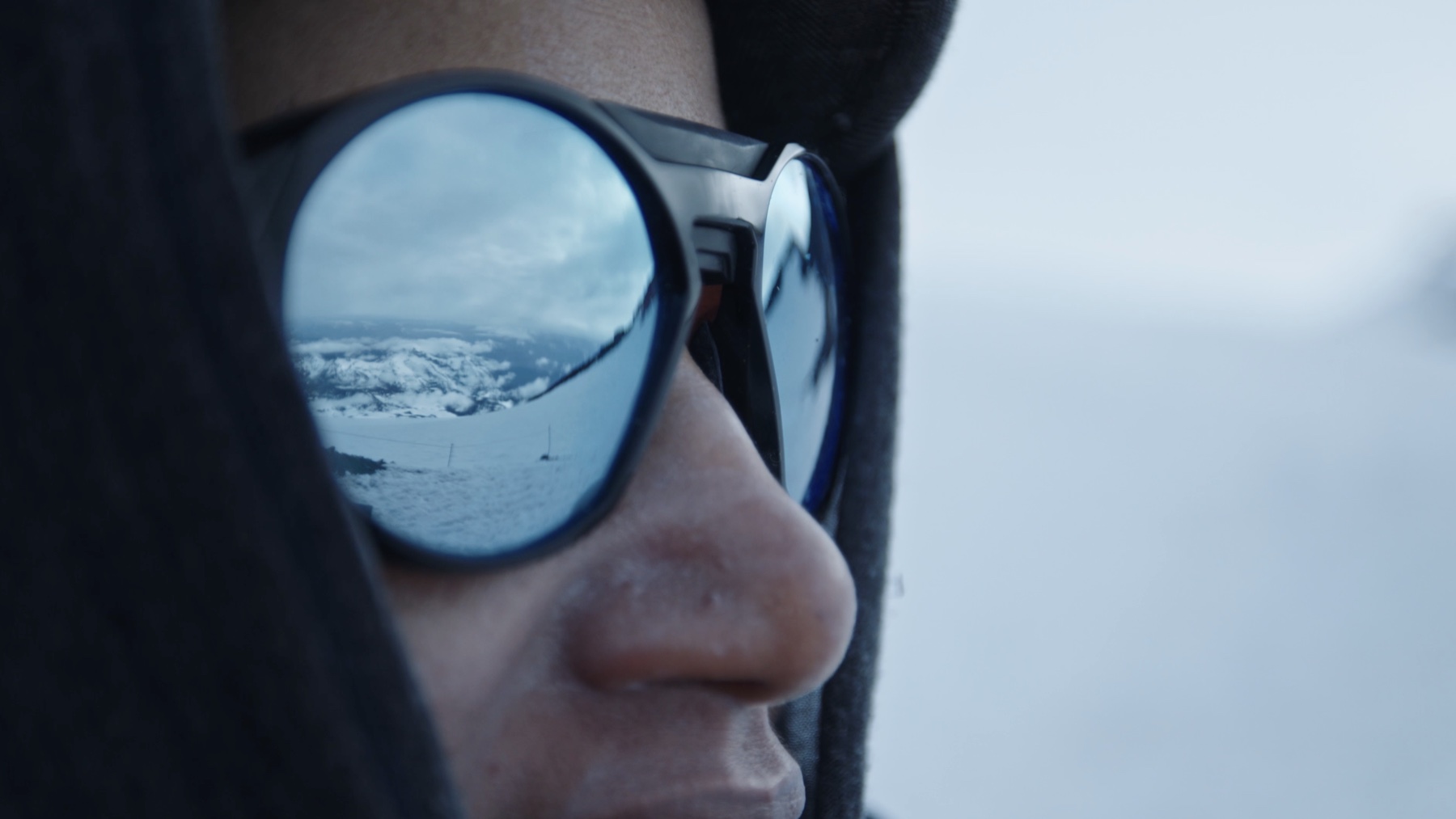 Snow-covered mountains reflected in a crew member’s glasses