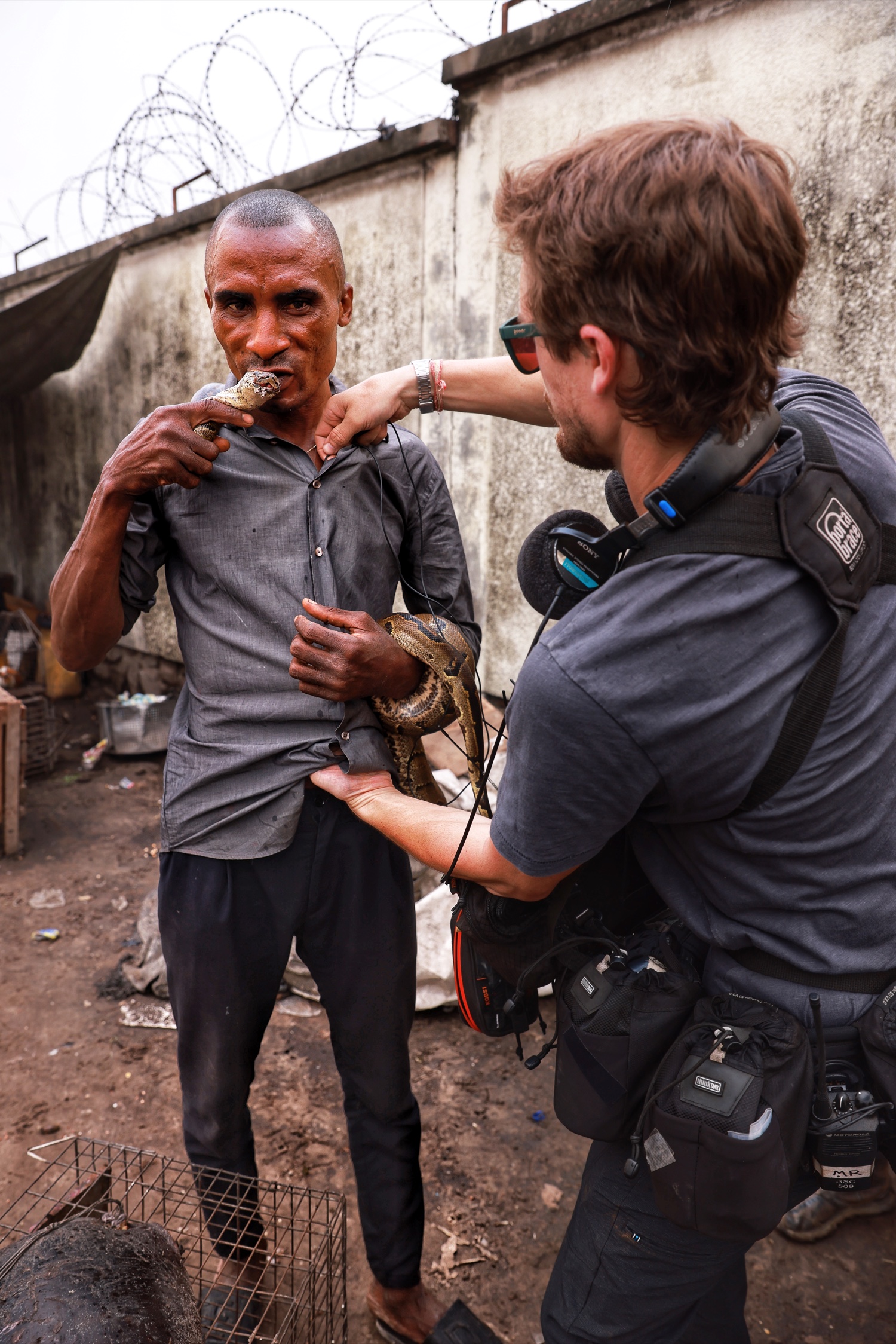 A sound recordist interviewing a man holding a snake