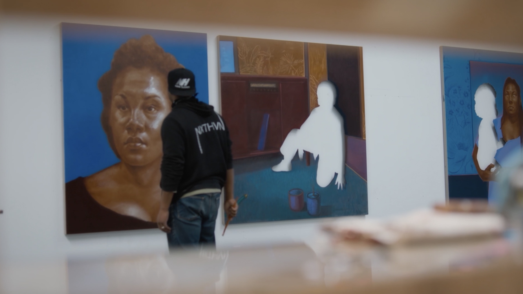 Titus Kaphar working among paintings in his studio